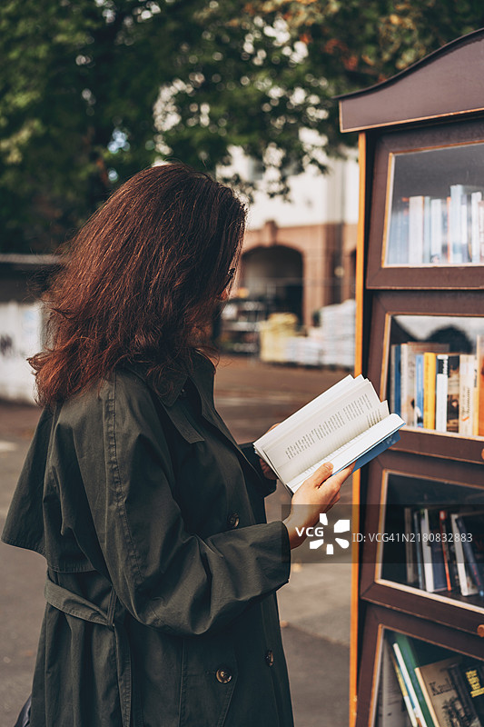 女人在户外公共书架旁读书图片素材
