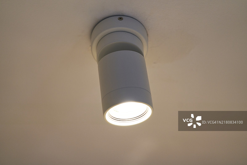 客厅里的吸顶灯在傍晚投射出明亮而集中的光线，简约设计，现代装饰图片素材