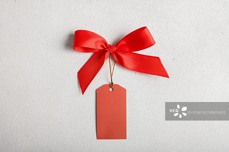 白色纹理背景上的红色蝴蝶结和空白标签图片素材
