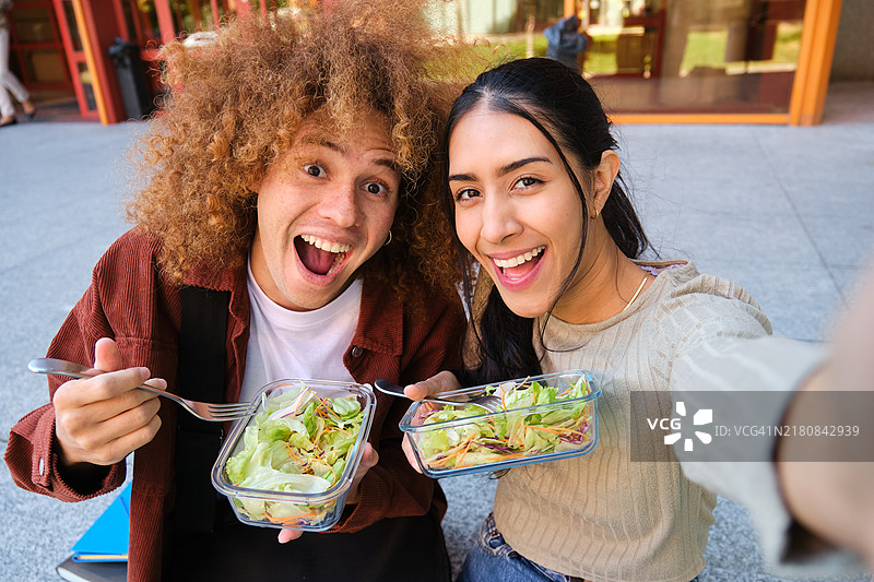在户外吃沙拉和自拍的快乐的跨种族学生图片素材
