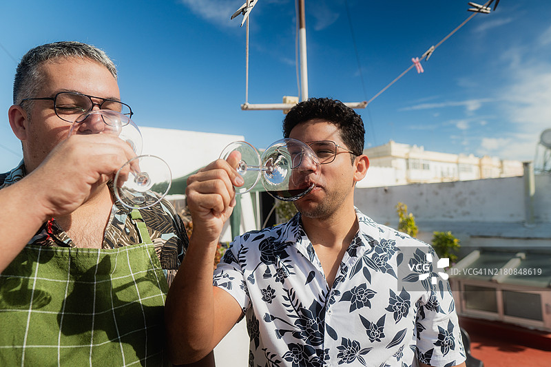 两个男人在阳光明媚的屋顶露台上品酒图片素材