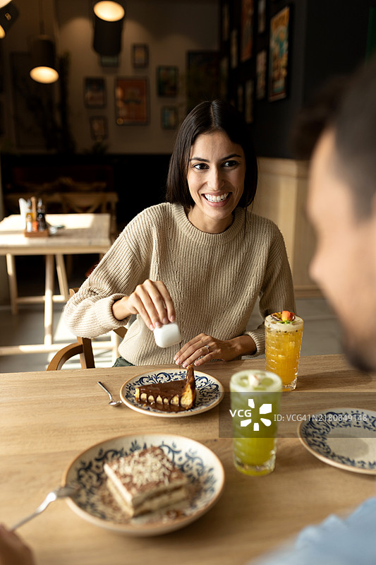 年轻漂亮的女性在美味蛋糕上淋上自制巧克力糖浆图片素材