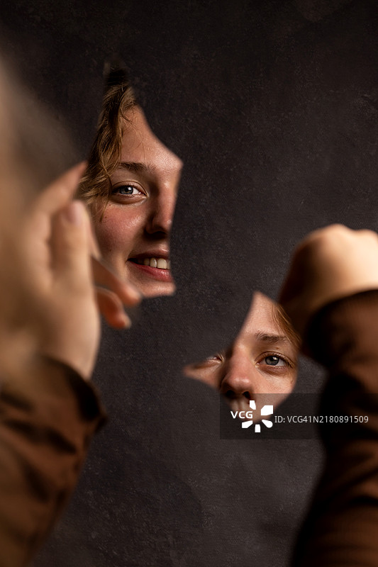 手掌中的镜子碎片与微笑女孩的面部图片素材