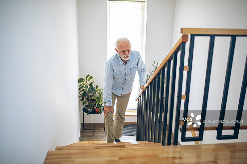 膝盖疼痛地爬楼梯的年长男人图片素材