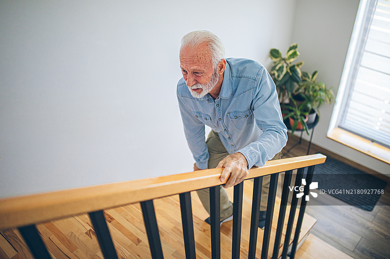 膝盖疼痛地爬楼梯的年长男人图片素材