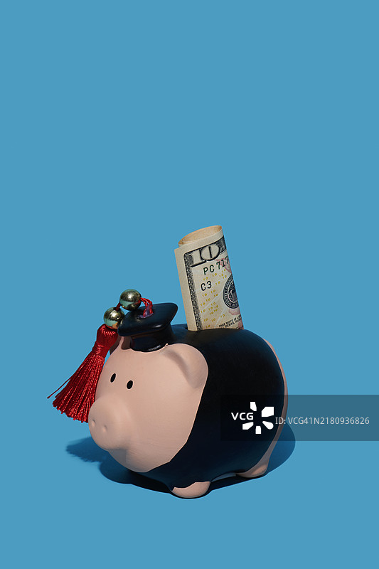 穿着学位服的存钱罐里的纸币图片素材