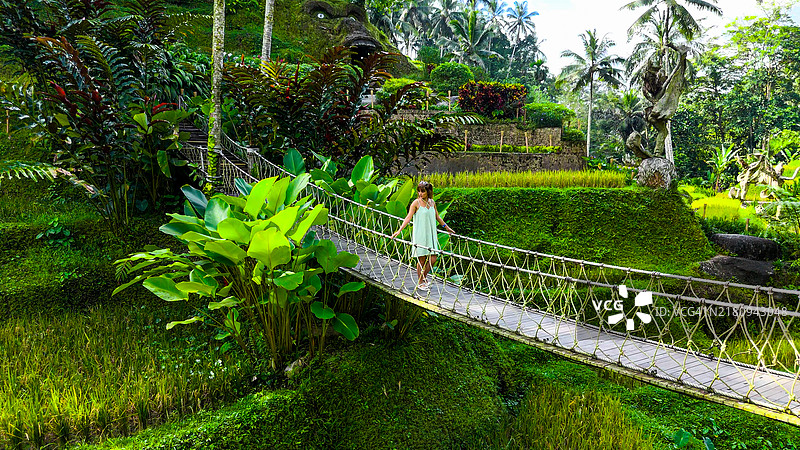 年轻旅行者走在德格拉朗梯田的木桥上航拍图片素材