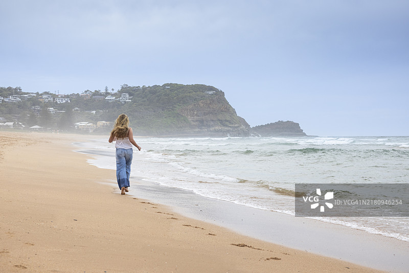 背影的少女在海滩上奔跑图片素材