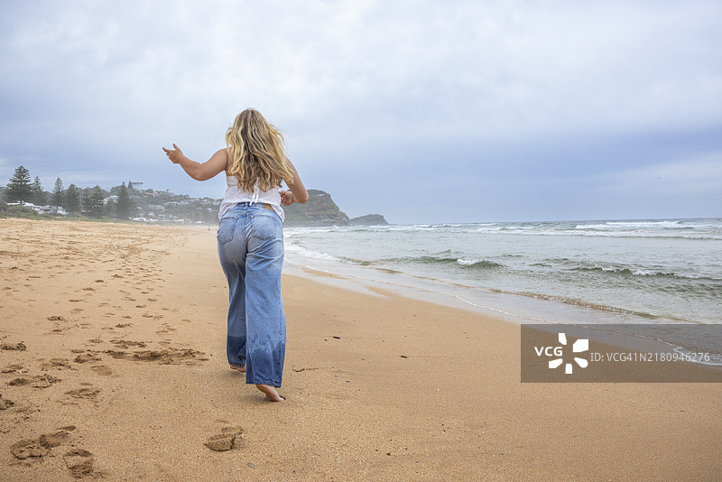 背影的少女在海滩上奔跑图片素材