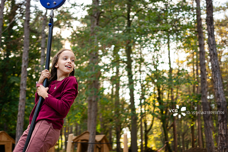 小女孩在森林里玩滑索图片素材