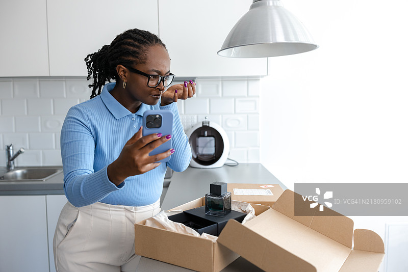 快乐的女人闻着新香水并拍摄社交媒体评论图片素材