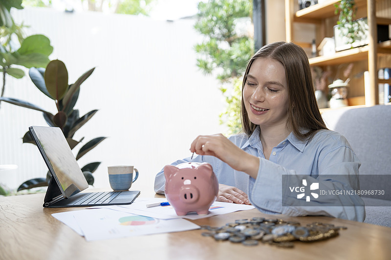 女人在存钱罐里存钱图片素材