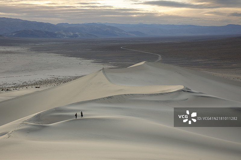 游客从加利福尼亚州死亡谷的尤里卡沙丘顶峰下山图片素材