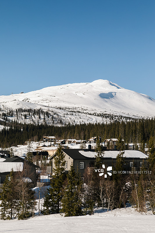 一座大型滑雪山，前景有山间小屋。图片素材