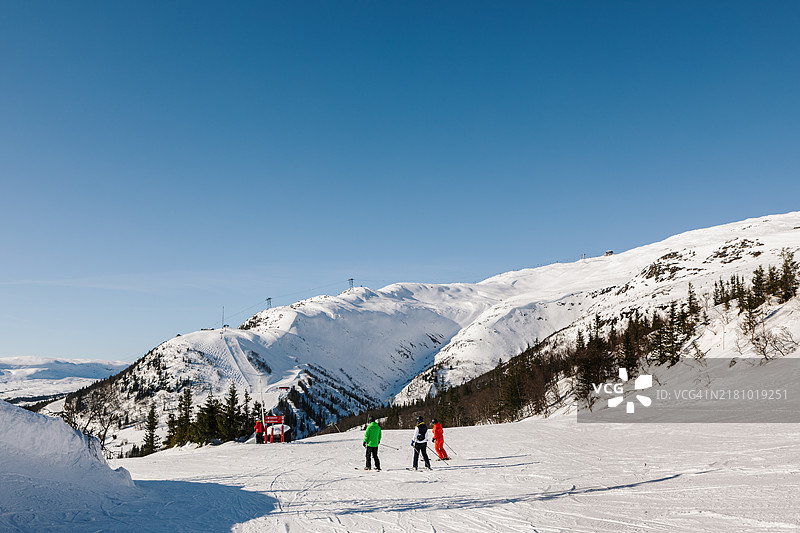 滑雪者在一个大型滑雪胜地，背景是山脉。图片素材