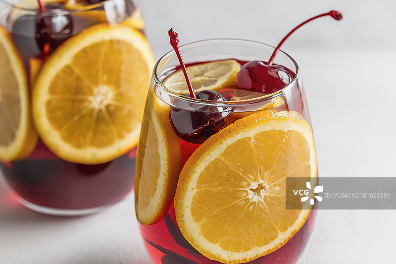 一杯清爽的饮料，装在透明的玻璃杯中，里面放满了橙子片、覆盆子和苹果。图片素材