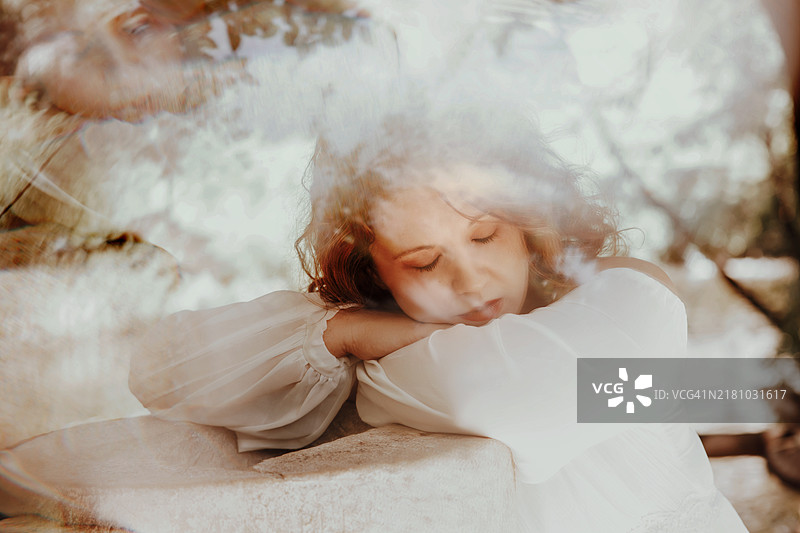 红发年轻女子肖像，闭着眼睛，头靠在手臂上，万花筒效果图片素材