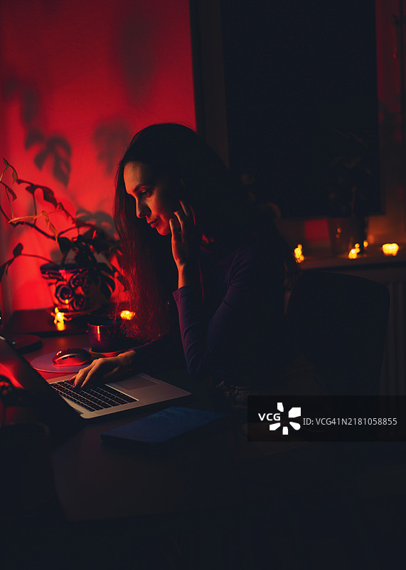 女性深夜工作：温馨的夜晚场景，伴随笔记本电脑和烛光图片素材