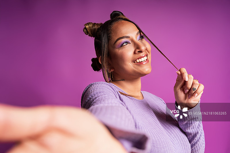 网红在紫色背景上用智能手机制作内容图片素材