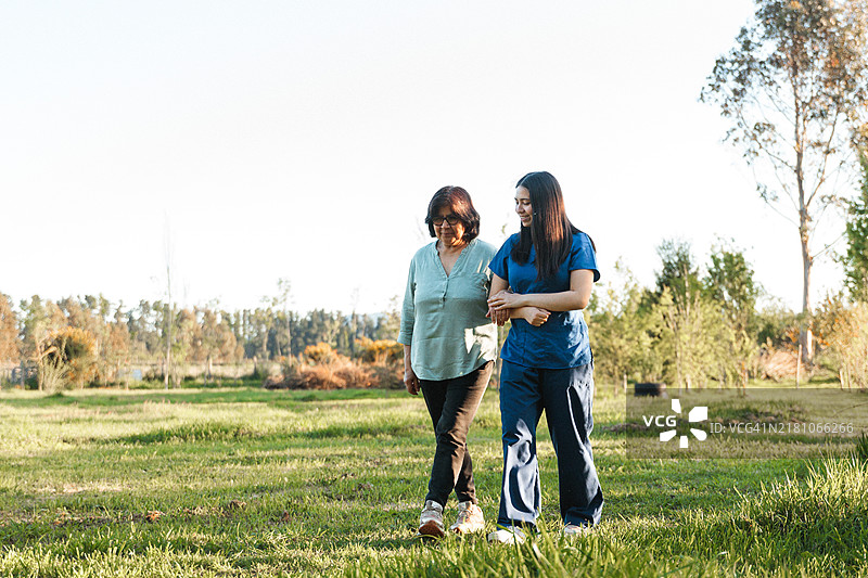 年长的成年人在乡村与她的护士悠闲地散步图片素材