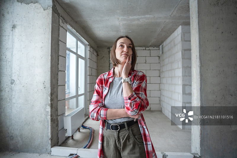 年轻女子在未完成的房屋装修内思考图片素材
