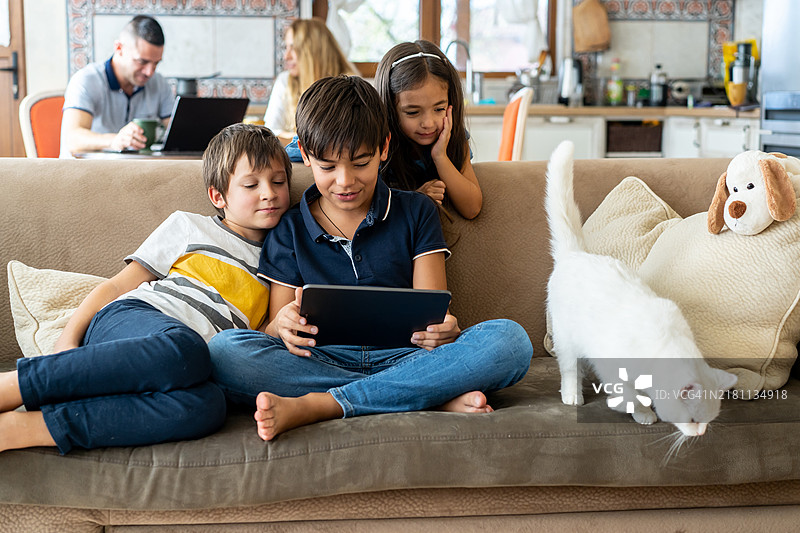 三个兄弟姐妹在便携设备上看电影图片素材