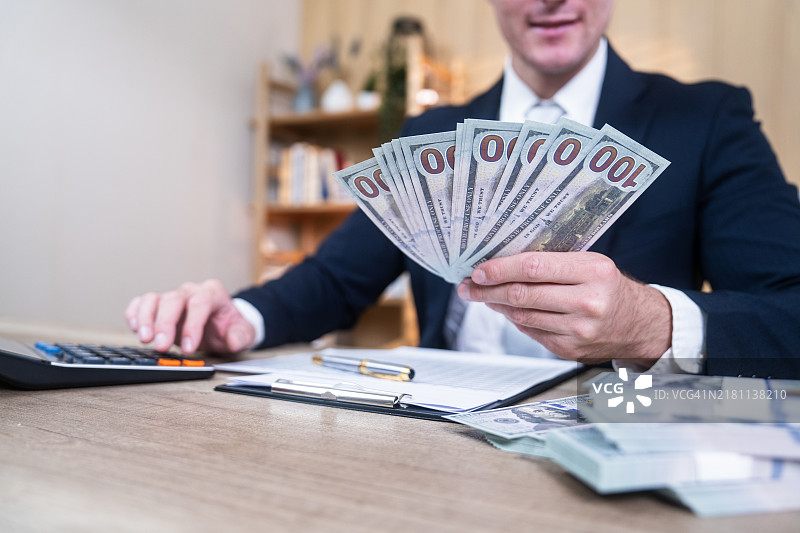 商人用计算器在办公桌上数钱图片素材