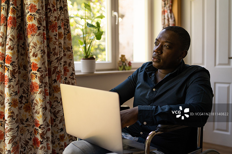 坐轮椅的男士在家用笔记本电脑工作图片素材