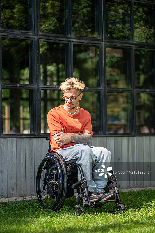 在公园里，悲伤的残疾人坐在轮椅上独自反思，面临心理健康的挣扎与孤独。图片素材
