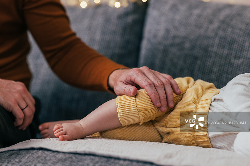 父亲在舒适的家庭环境中安慰沙发上的宝宝图片素材