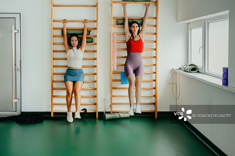 两名女子在健身房的肋木上锻炼图片素材