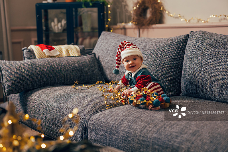 可爱的宝宝穿着圣诞服装在舒适的沙发上过节图片素材