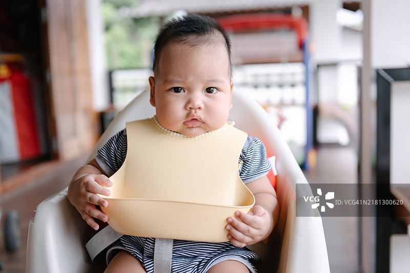 坐在高脚椅上等待喂食第一餐的可爱男婴图片素材