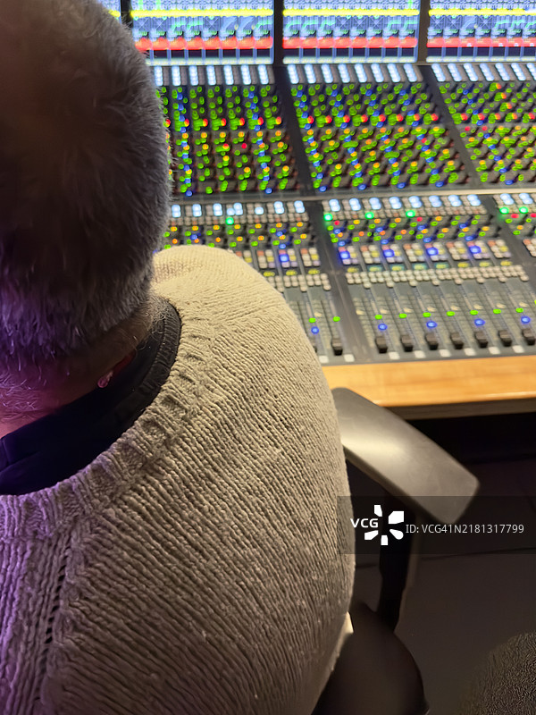 中年男子在他的音响工作室操作调节不同音轨的桌子图片素材