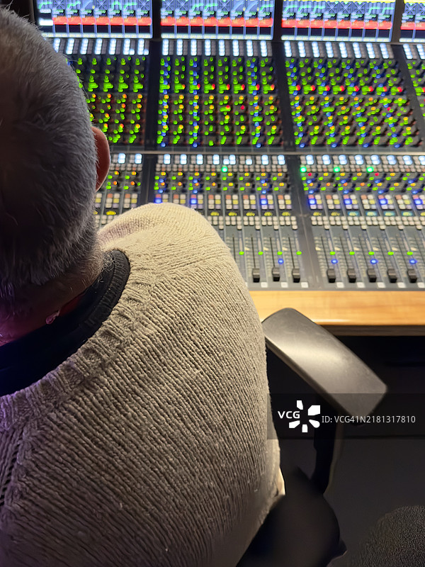 中年男子在他的音响工作室操作调节不同音轨的桌子图片素材