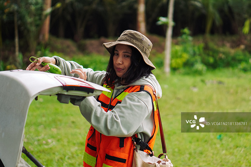 志愿者女性在户外田野中整理汽车后备箱图片素材