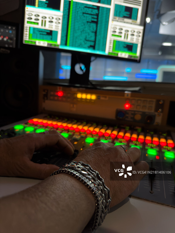 中年男子在他的音响工作室操作调节不同音轨的桌子图片素材