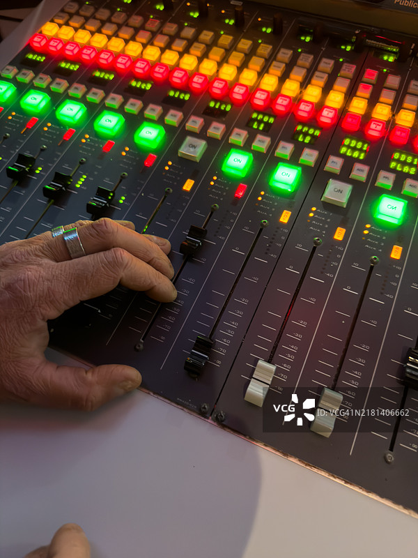 中年男子在他的音响工作室操作调节不同音轨的桌子图片素材