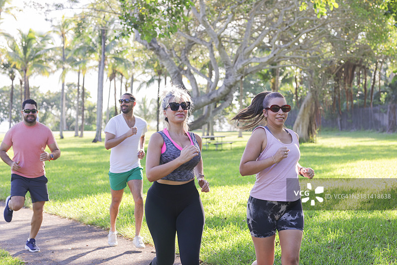 一小群拉丁裔千禧一代的人穿着运动服在公园里一起跑步。图片素材