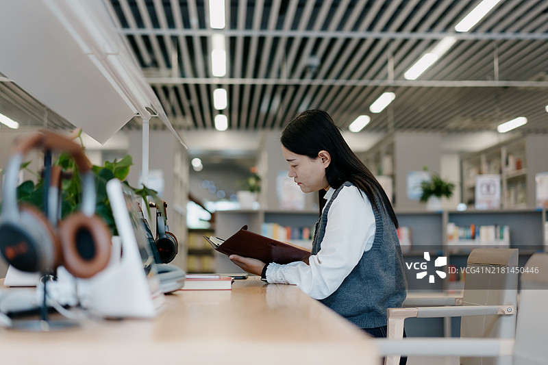 亚洲女士在图书馆使用智能手机图片素材