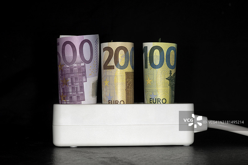 电费的象征图片，插座与500欧元、200欧元和100欧元纸币，黑色背景工作室摄影图片素材