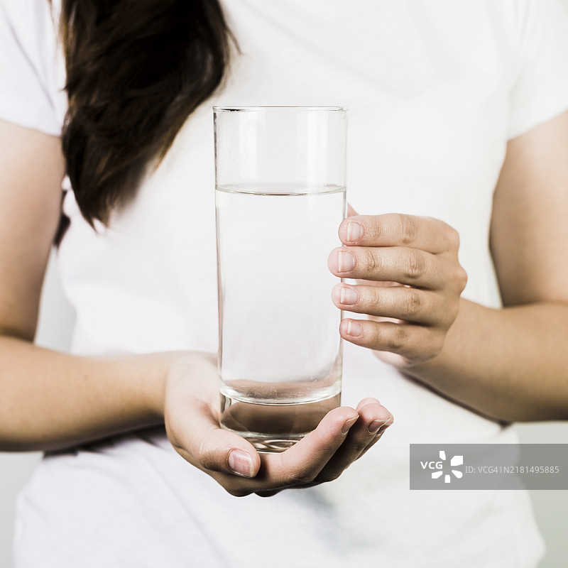 女性手持玻璃杯喝水图片素材