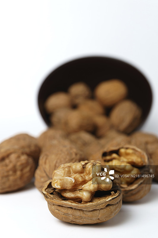 白色背景上孤立的棕色碗中的核桃图片素材