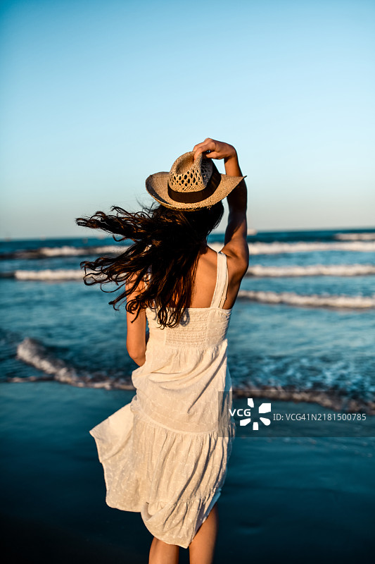 穿着白色飘逸连衣裙的漂亮女人望着大海陷入沉思图片素材