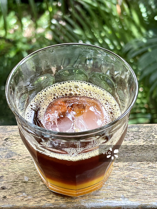 木桌上放着一杯冰咖啡和百香果汁的玻璃杯图片素材