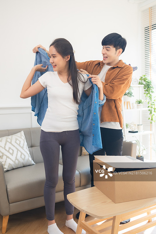 年轻的亚洲夫妇打开从网上商店收到的衣服，接收并打开网购的概念图片素材