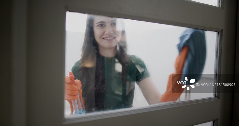 自信的女人在家擦拭窗户图片素材