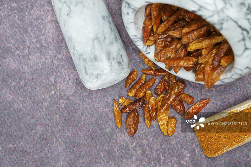 白色大理石研钵中的完整卡宴辣椒和木勺中的卡宴辣椒粉图片素材