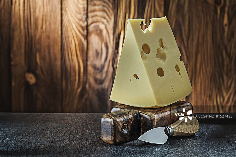 放在木制砧板上的大块牛奶味马斯丹奶酪与刀具图片素材