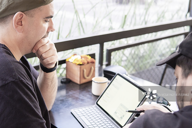 在户外酒吧看平板电脑的两个男人图片素材